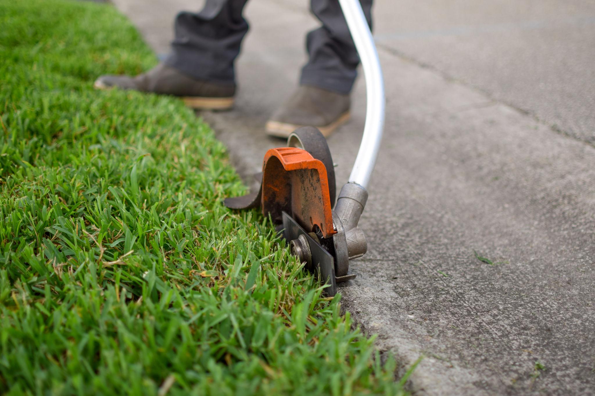 Lawn edging services in Central Valley creating a precise border along a residential walkway.